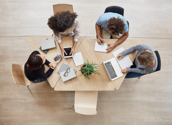 View from above. Business,startup, teamwork concept. Startup partners sitting at coworking space talking about future project, looking through examples of work on laptop and digital tablet